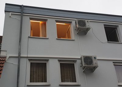 ein weißes Gebäude mit zwei Klimaanlagen an der Seite.