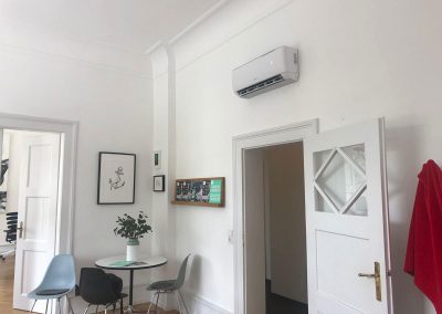 ein Raum mit Tisch, Stühlen und Klimaanlage.