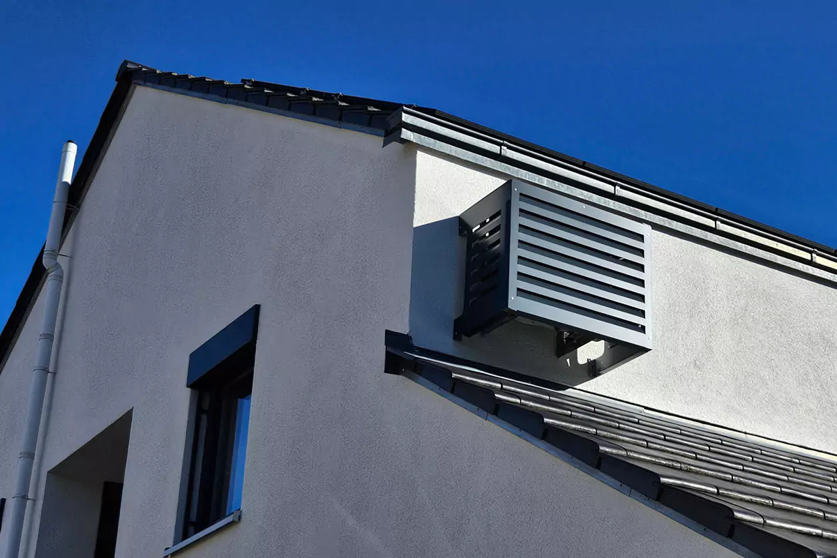 Moderne Gebäudefassade mit kontrastierenden geometrischen Linien und Schatten vor einem klaren blauen Himmel.